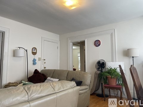 A living room with a couch, a fan, and a plant.