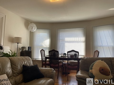 A living room with a couch, chairs, and a dining table.