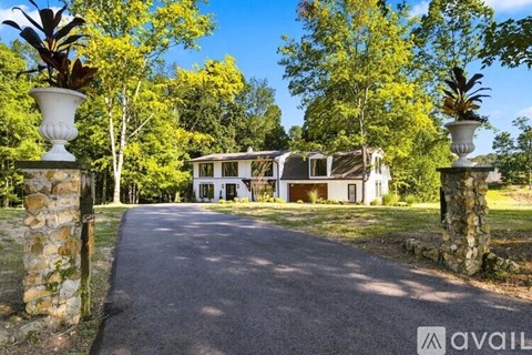 A house is surrounded by trees and has a driveway leading to the front door.