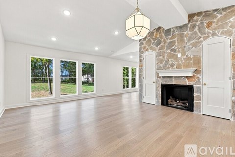 A spacious room with a stone fireplace and a large window overlooking a green landscape.