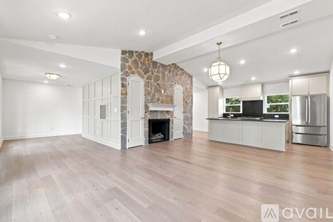 A spacious living room with a stone fireplace and wooden flooring.
