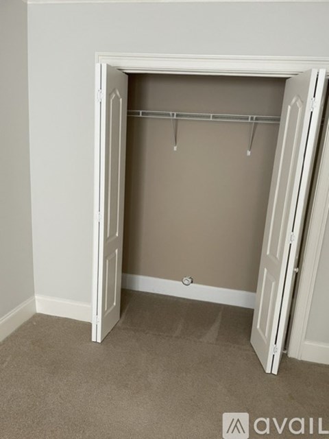 A white closet with a carpeted floor and a beige wall.