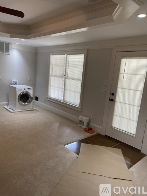A room with a washing machine and a fan on the floor.