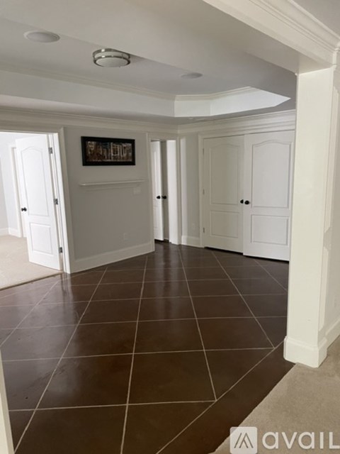 A room with white walls and brown tile flooring.