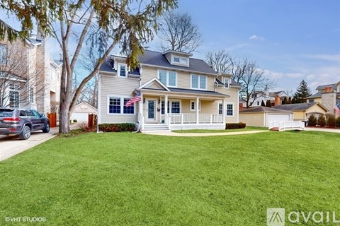 A house with a lawn and a tree in front of it.