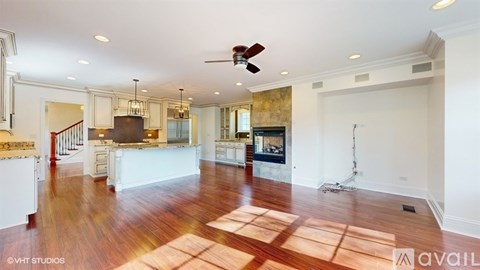 A spacious living room with hardwood floors and a central fireplace.