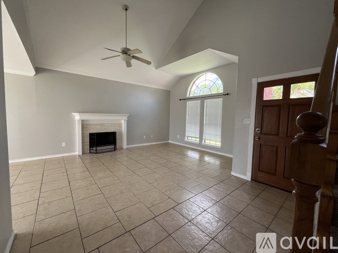 A spacious living room with a fireplace and a ceiling fan.