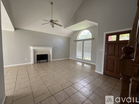 A spacious living room with a fireplace and a ceiling fan.