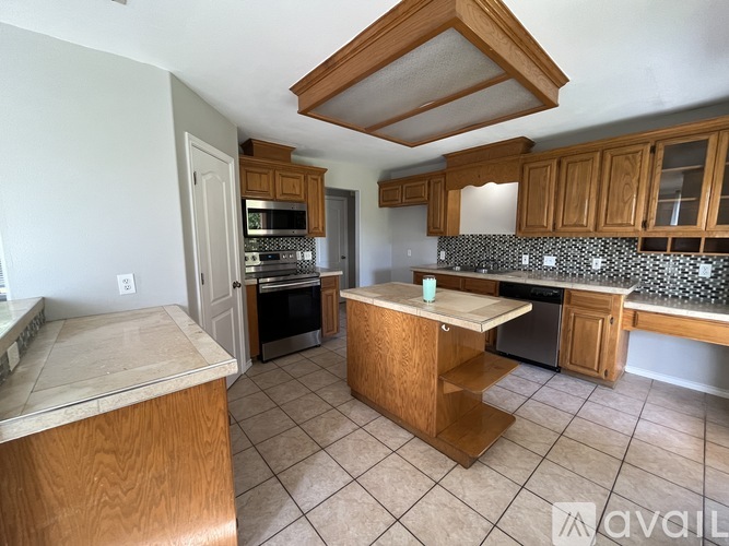 A kitchen with wooden cabinets and a tile floor.