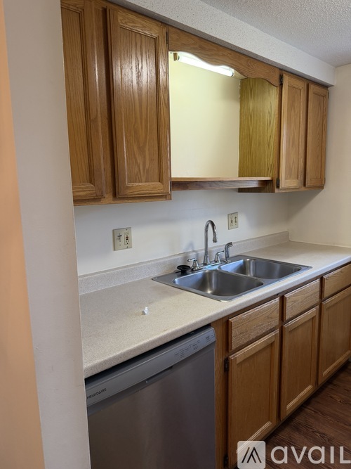 A kitchen with wooden cabinets and a stainless steel dishwasher.