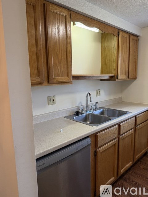 A kitchen with wooden cabinets and a stainless steel dishwasher.