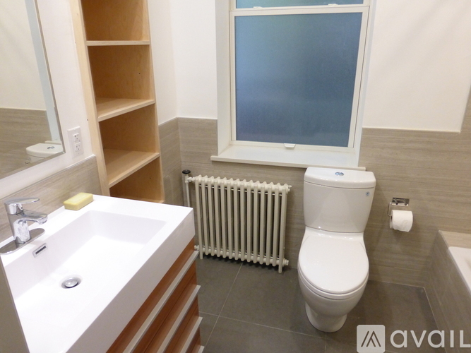 A bathroom with a toilet, sink, and window.