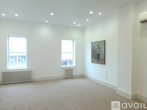 A spacious room with two windows and a painting on the wall.