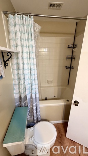 A small bathroom with a toilet, a shower with a curtain, and a towel rack.