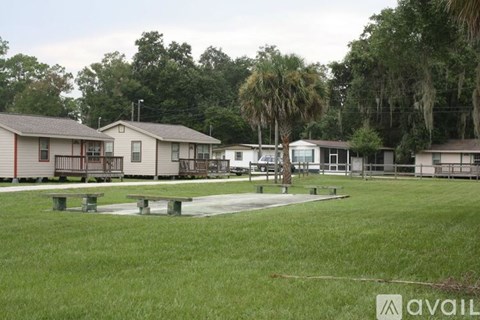 A grassy area with benches and a row of houses in the background.