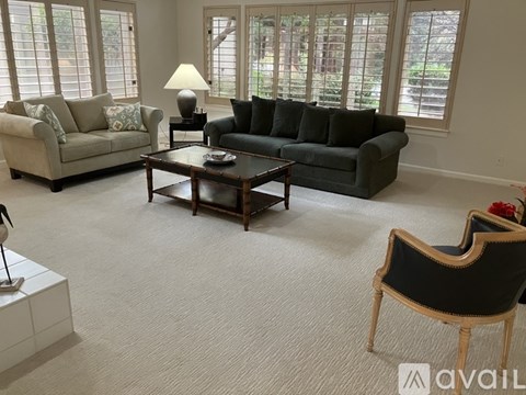 A living room with a grey couch, a black couch, and a wooden coffee table.