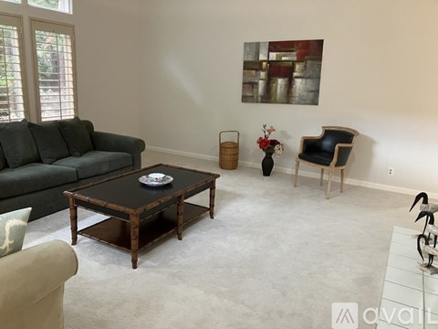 A living room with a grey couch, a coffee table, and a painting on the wall.