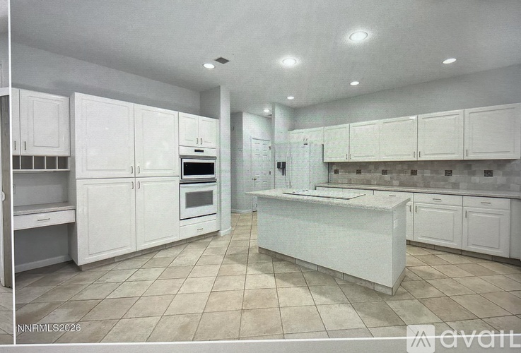 A spacious kitchen with white cabinets and a central island.