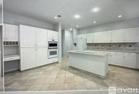 A spacious kitchen with white cabinets and a central island.