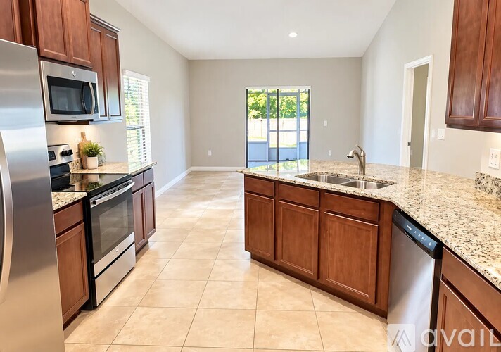 A kitchen with a refrigerator, microwave, oven, and sink.