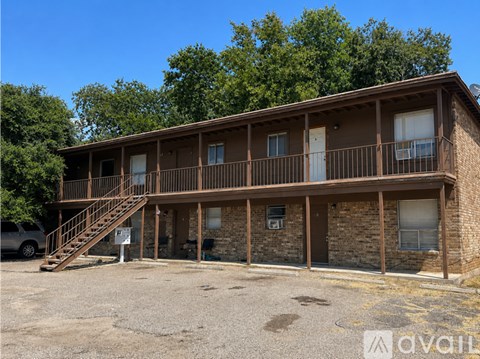 A two-story brick apartment building with a balcony on the second floor.