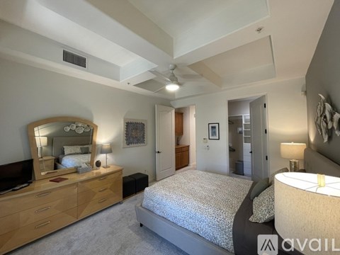 A bedroom with a large bed, a dresser with a mirror, and a ceiling fan.