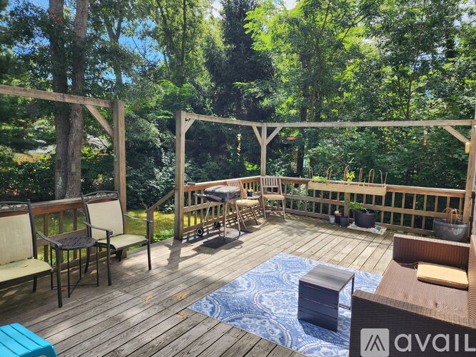 A wooden deck with chairs and a table surrounded by trees.