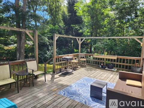 A wooden deck with chairs and a table surrounded by trees.