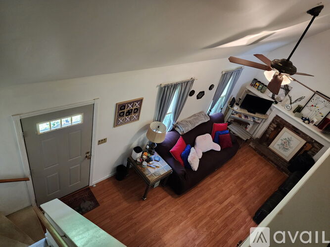 A living room with a couch, a fan, and a television.