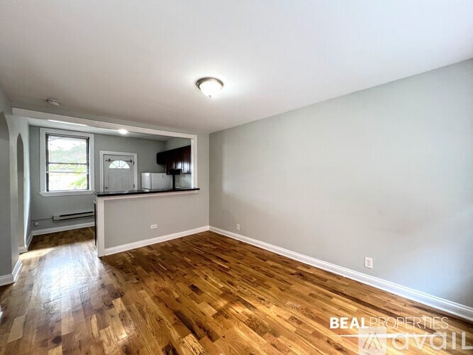 A room with wooden floors and a window with a view of trees.