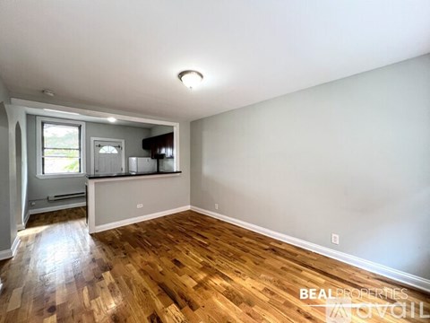A room with wooden floors and a window with a view of trees.