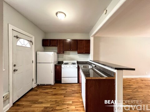 A kitchen with white appliances and wooden floors.