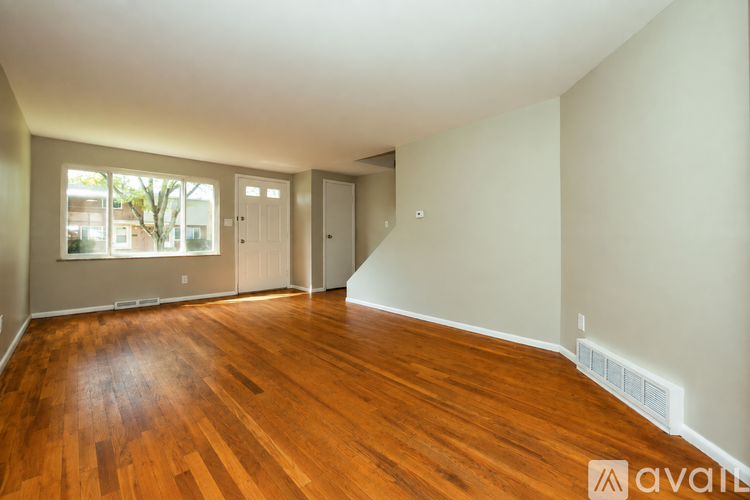 A room with wooden floors and white walls is available for rent.