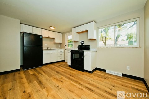 A kitchen with black appliances and wooden floors.