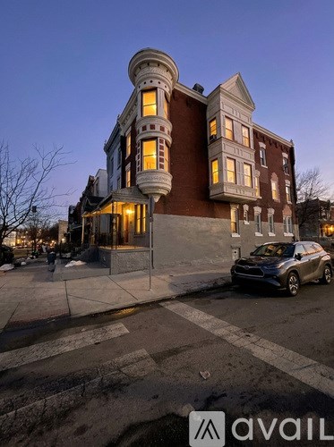 A car is parked in front of a large building with a curved corner.