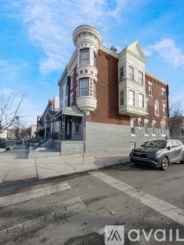 A car is parked on the street in front of a brown and white building.