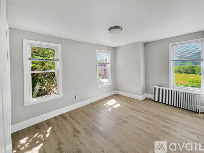 A spacious room with two windows and a radiator on the wall.