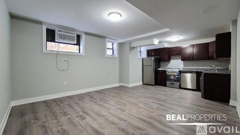 A spacious room with a kitchenette and a window.
