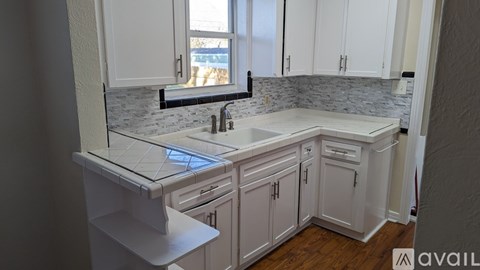 A kitchen with white cabinets and a marble countertop.