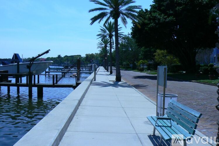 A bench is on a concrete walkway next to a body of water.