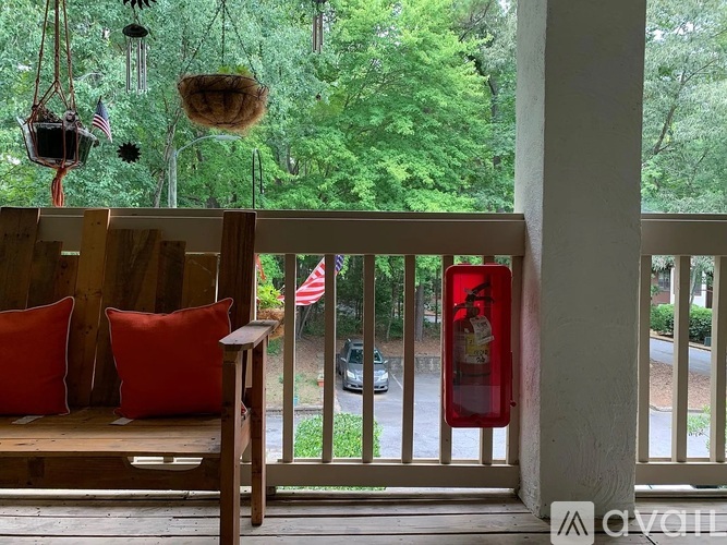 A balcony with a bench, pillows, and a view of a street.