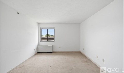 A large empty room with a window and a white piece of furniture.