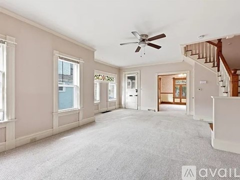 A spacious room with a fan and a staircase.