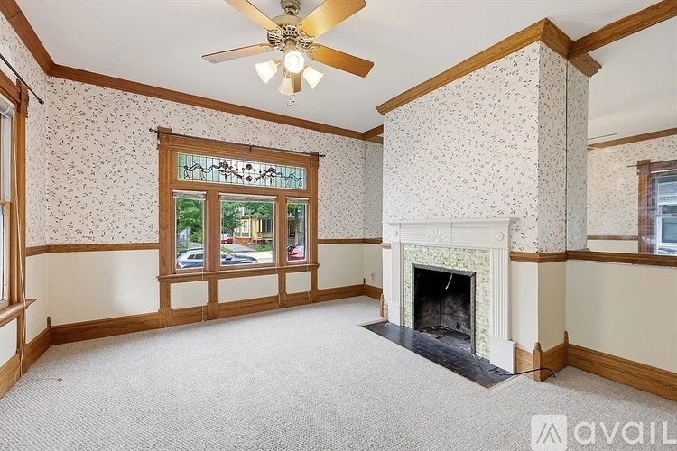 A living room with a fireplace and a ceiling fan.