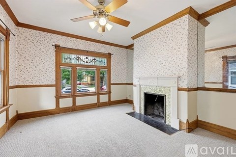 A living room with a fireplace and a ceiling fan.