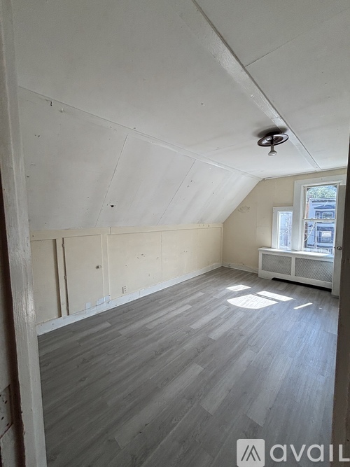 A room with wooden flooring and a window with blinds.