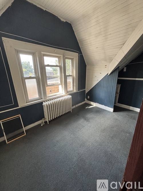 A room with a window, a radiator, and a picture frame on the floor.