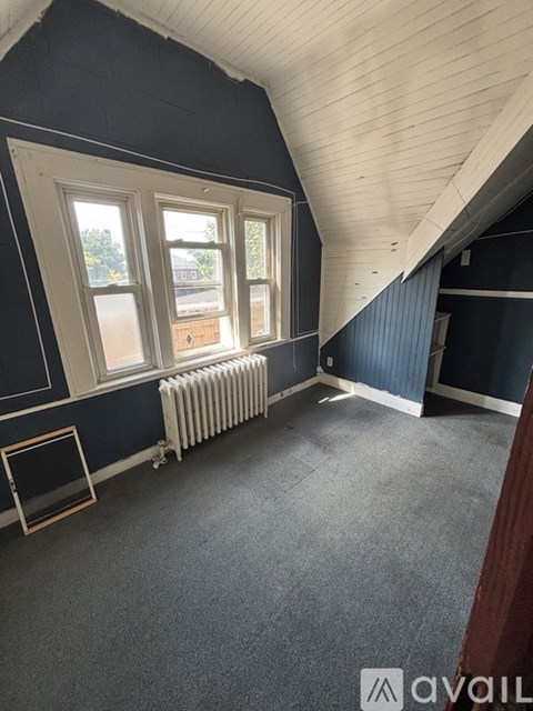 A room with a window, a radiator, and a picture frame on the floor.