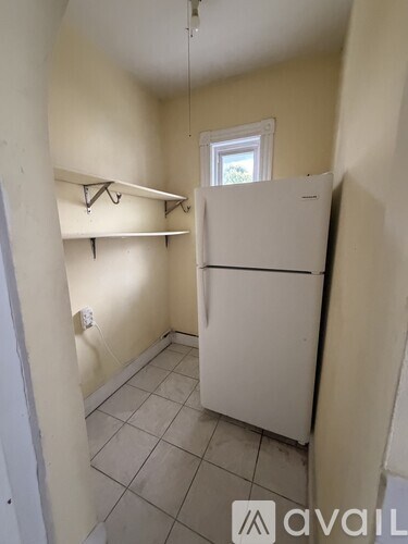 A small kitchen with a white fridge and a window.