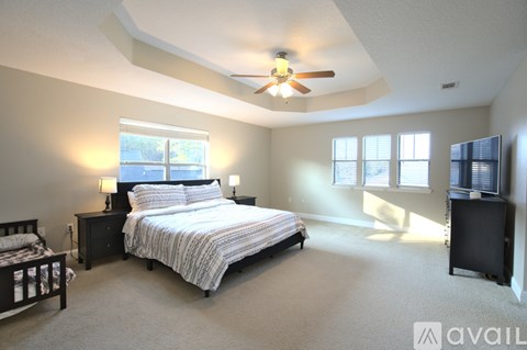 A bedroom with a large bed and a ceiling fan.